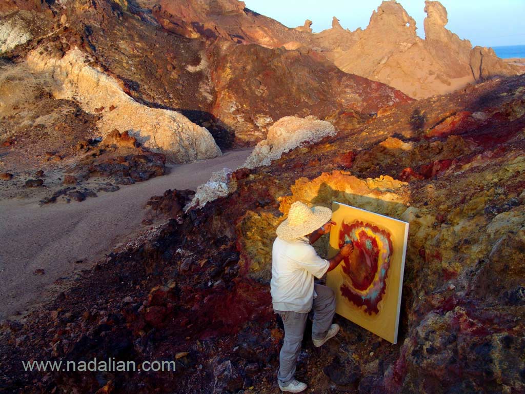 احمد نادعلیان در حال نقاشی با خاک ها و شن های رنگی بر روی بوم در محیط طبیعی جزیره هرمز
