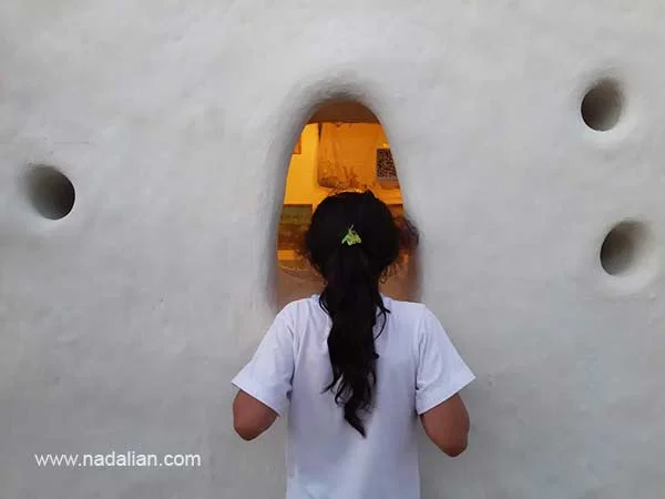 دختری از لاقت نقاشی های داخل را از پنجره کوچک تماشا می کند، ورودی خانه دکتر نادعلیان در بندر تاریخی لافت