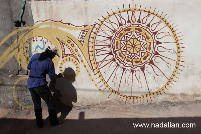 حمید خندان در حال نقاشی دیواری کوچه های مسیر هنرمند سرا و موزه فعلی دکتر نادعلیان در جزیره هرمز
